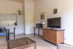 a living room with a flat screen tv and a kitchen at Beach appartement 40 in Callantsoog