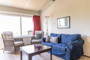 a living room with a blue couch and chairs at Beach appartement 40 in Callantsoog