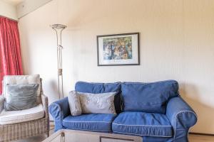 a blue couch and a chair in a living room at Beach appartement 40 in Callantsoog