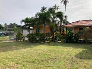 a house with palm trees in front of a yard at Baan Kebsap บ้านเก็บทรัพย์ in Ko Yao Noi