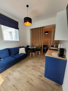 a living room with a blue couch and a kitchen at Cicha 3 in Sztutowo