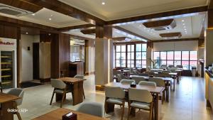 a dining room with tables and chairs and windows at SUNDHA HOTEL palanpur in Pālanpur