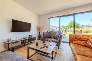 a living room with a couch and a tv at Ti Braz Magnifique Maison Piscine in Plouguerneau