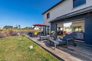 a wooden deck with chairs and tables on a house at Ti Braz Magnifique Maison Piscine in Plouguerneau