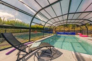 a swimming pool with a glass roof and a chair next to it at Ti Braz Magnifique Maison Piscine in Plouguerneau