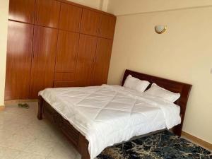 une chambre avec un grand lit avec une tête de lit en bois dans l'établissement Thika Furnished Apartments, à Thika