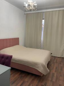 a bedroom with a large bed and a chandelier at Laguna City Lux in Tegirmenty