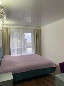 a bedroom with a bed and a window at Laguna City Lux in Tegirmenty