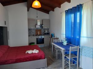 a room with a bed and a table and a kitchen at Villa Erilia in San Giovanni Suèrgiu