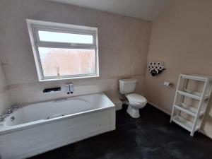 a bathroom with a tub and a toilet and a window at Cinematic Journeys in Nottingham