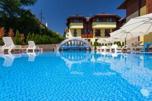 a swimming pool with chairs and umbrellas in front of a building at Vila Barović and Spa in Zlatibor