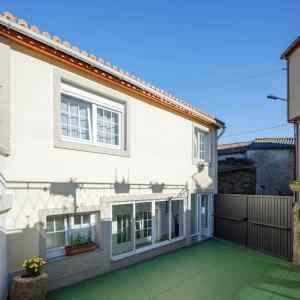 a white house with a green floor and windows at Casa Pilara in Lousame