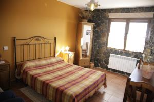 - une chambre avec un lit avec une couverture rayée et une fenêtre dans l'établissement Hostal Restaurante Alto Rey, à Arroyo de las Fraguas