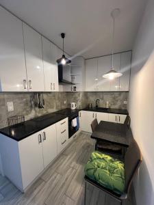 a kitchen with white cabinets and a table with a green seat at Cosy Rooms in Kraków