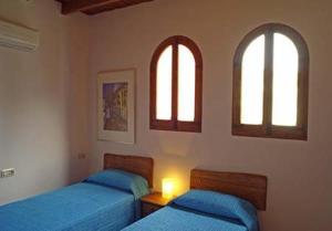 2 camas en un dormitorio con 2 ventanas en Casa Figueretes, en Finestrat