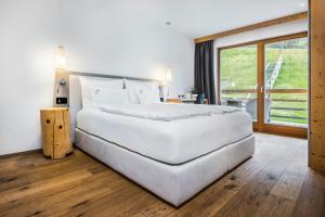a large white bed in a room with a window at Bio Alpine Hotel Gran Fodà in San Vigilio Di Marebbe