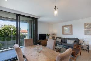 Central Southern Suburbs Leafy Village Neighbourhood في كيب تاون: غرفة معيشة بها طاولة وأريكة