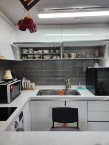 cocina con fregadero y silla negra en Gangneung Solhyang Hue House, en Gangneung