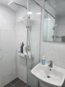 Un baño blanco con ducha y lavabo. en Gangneung Solhyang Hue House, en Gangneung