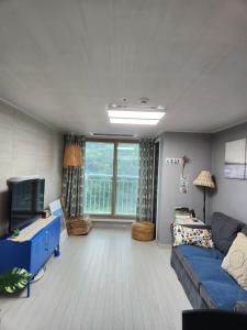 Una sala de estar con un sofá azul y un televisor. en Gangneung Solhyang Hue House, en Gangneung