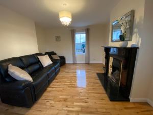 a living room with a black leather couch and a fireplace at Young House in Gracefield