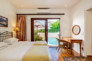 a bedroom with a bed and a desk and a window at Camps Bay Terrace Lodge in Cape Town