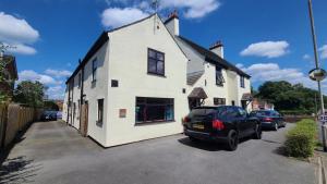 a white house with a car parked in a parking lot at The Garden Room in Hednesford