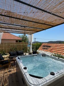 a hot tub under an umbrella on a patio at Rural home Basin dvor with jacuzzi in Vinišće