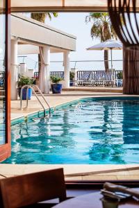 a swimming pool with chairs and an umbrella at Portixol Hotel & Restaurant in Palma de Mallorca