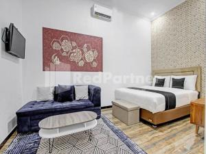 a bedroom with a bed and a couch and a tv at House n Coffee 55 Temanggung RedPartner in Temanggung