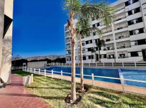 a palm tree next to a building with a swimming pool at Appartement à louer Complexe City Center in Oued Laou