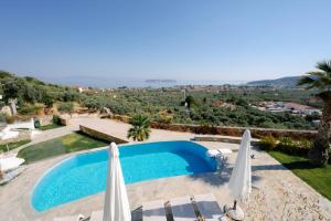 a pool with two umbrellas and a view of a city at Hillside Villa - Pnoe in Limenas