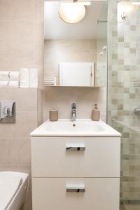 Un baño blanco con lavabo y espejo. en Bright and Cozy 1BD Flat in Plovdiv with Parking by Flat Mаnager, en Plovdiv