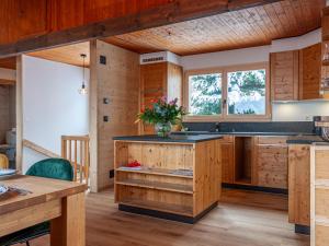 eine Küche mit Holzschränken und einer Theke mit Blumen darauf in der Unterkunft Chalet Le Loup- le Renard et la Belette by Interhome in Nendaz