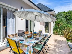 a table with an umbrella on a patio at Holiday Home Maison de Locmaria by Interhome in Ploemel