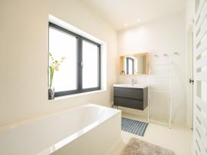 a white bathroom with a tub and a sink at Holiday Home La Gabane quiet but central house by Interhome in De Haan