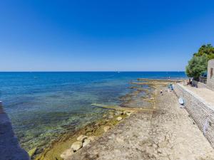 a group of people standing on a beach near the water at Apartment Darja by Interhome in Novigrad Istria
