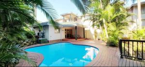 a swimming pool in front of a house with palm trees at Ramsgate Beachfront - Ramsgate Palms AA 50 in Margate