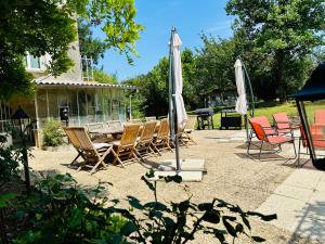 a group of chairs and umbrellas on a patio at Le Pavillon, Grand Manoir du XVIIe avec Piscine, Bain Nordique et accès privé à la Charente in Alloué