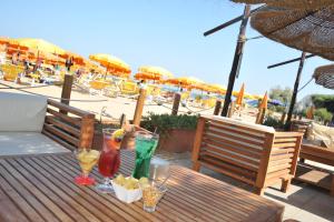 un tavolo in legno con bevande sulla spiaggia con ombrelloni di Albergo Torrente a Vieste Altre 53 foto