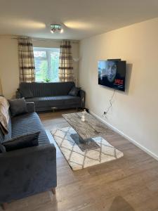 a living room with a couch and a tv on the wall at Eastpark 5 bdrms Walk to O2 Apollo and City in Manchester