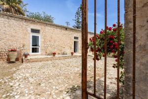 a stone building with red flowers in front of it at Case Mediterranee in Modica