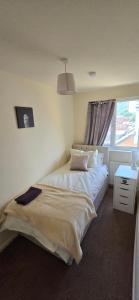 a bedroom with a large bed and a window at Eastpark 5 bdrms Walk to O2 Apollo and City in Manchester