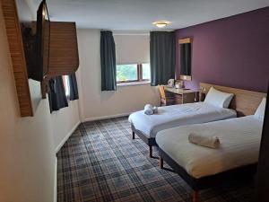 a hotel room with two beds and a window at Britannia Edinburgh Hotel in Edinburgh