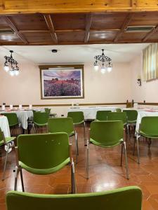 a room with green chairs and tables and a painting at Grifone Hotel in Perugia