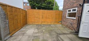 a wooden privacy fence next to a brick building at Eastpark 5 bdrms Walk to O2 Apollo and City in Manchester +15 photos