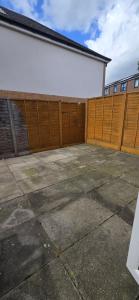 a garage with a wooden fence next to a building at Eastpark 5 bdrms Walk to O2 Apollo and City in Manchester