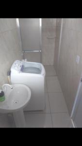 a white bathroom with a toilet and a sink at Casa com Piscina e Ar Condicionado in Imbé