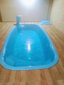 a large blue tub in a room with a wooden floor at Casa com Piscina e Ar Condicionado in Imbé