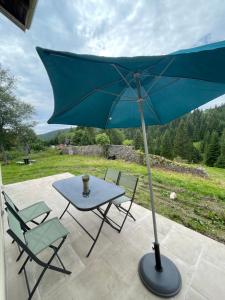 a table and chairs with a blue umbrella on a patio at Le petit jurassien 2 in Bellefontaine